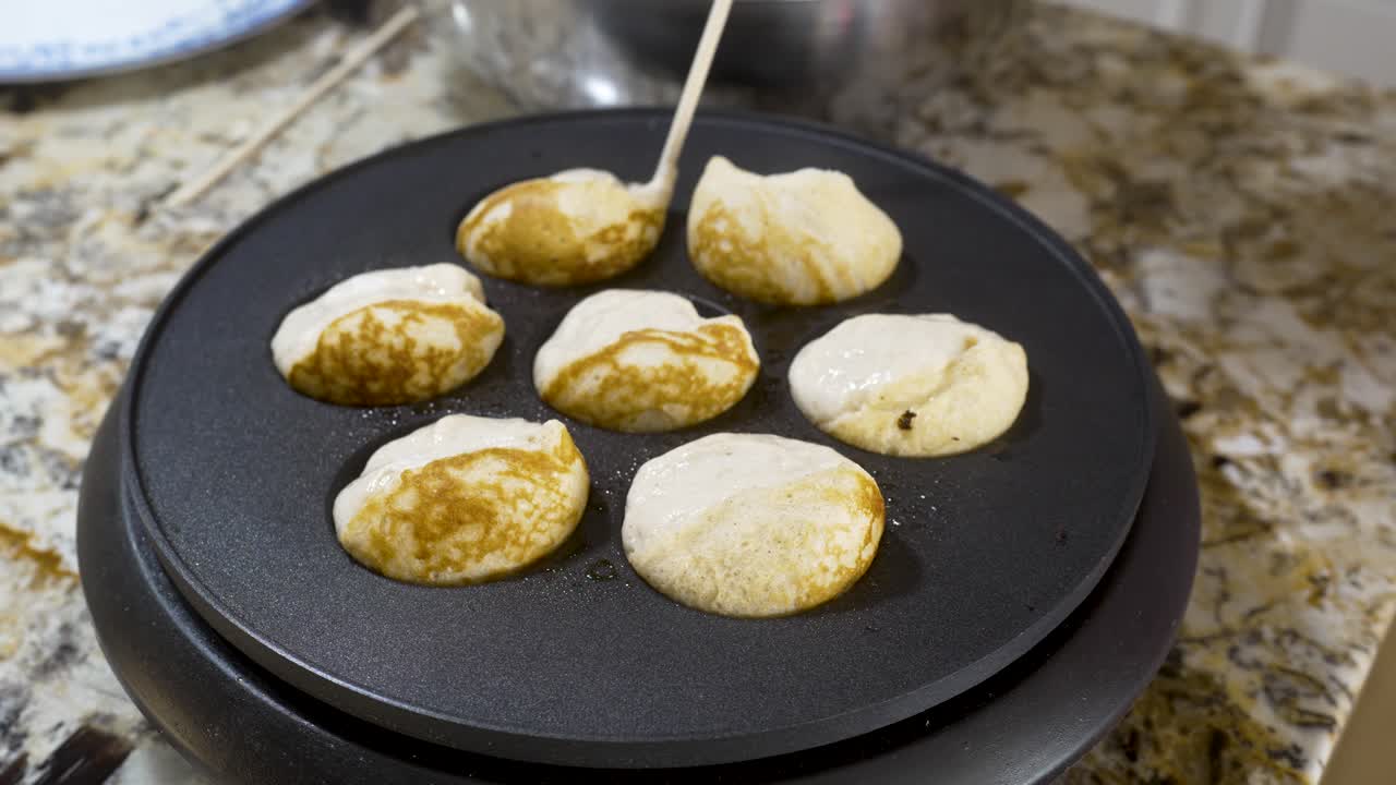 Menggunakan stik kayu untuk membalik aebleskiver di wajan agar matang menjadi bentuk bola - SERI AEBLESKIVER