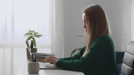 Una-Mujer-Independiente-Está-Escribiendo-Un-Mensaje-En-Una-Computadora-Portátil-Sentada-En-La-Mesa-En-La-Oficina-En-Casa,-Trabajando-En-Internet-Desde-Casa,-Traductora-O-Redactora