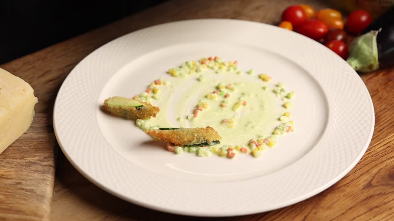 Chef che impiattano zucchine fritte con salsa cremosa e verdure a cubetti