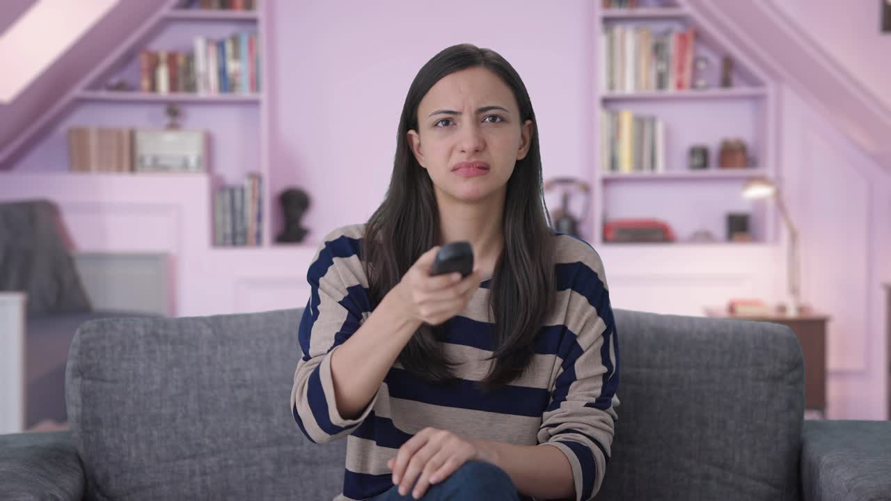 chica india tratando de arreglar el control remoto de la televisión