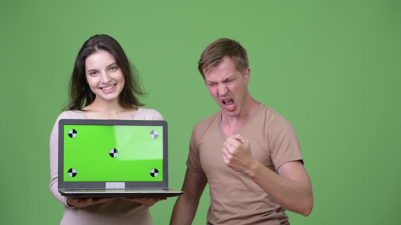 una pareja feliz mostrando una computadora portátil y recibiendo buenas noticias juntos