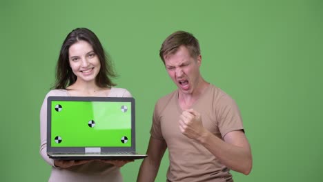 young happy couple showing laptop and getting good news together