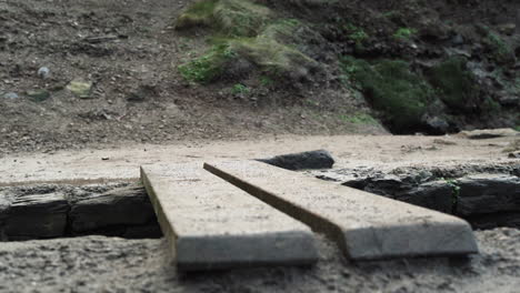 una chica caminando con botas negras pasando por una pequeña tabla de madera cerca de la costa - disparo de bajo nivel