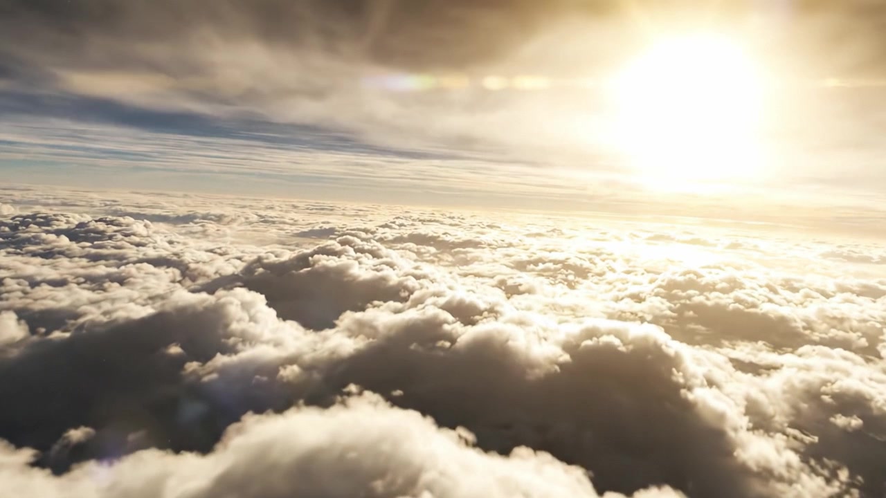 Una vista mozzafiato del sole che sorge sopra le nuvole, illuminando il cielo con luce calda e proiettando ombre sulla soffice formazione nuvolosa sottostante.