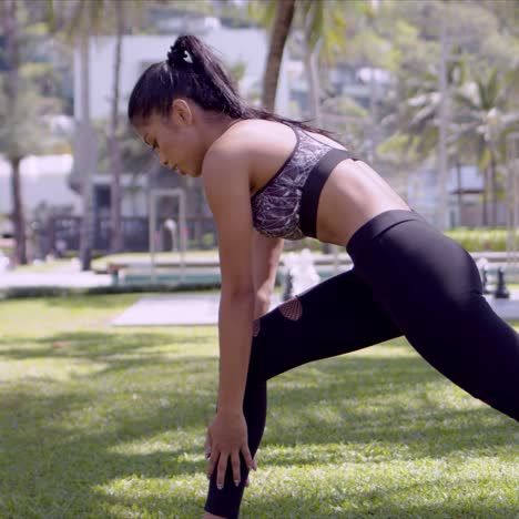 mujer asiática activa estirándose diligentemente en el parque