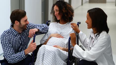 doctor interacting with pregnant woman in corridor