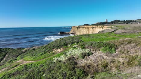 Sweeping-shot-over-green-fields-revealing-pacific-coast-shore,-California