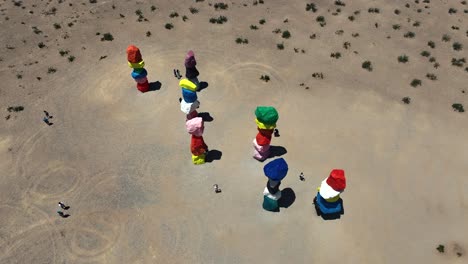 7-Magic-Mountains-large-boulders-installation-by-artist-Ugo-Rondinone,-aerial-rising-in-the-middle-of-the-Nevada-desert