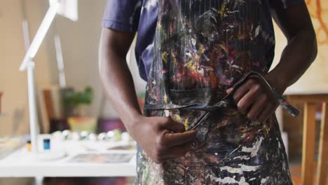 Afroamerikanischer-Männlicher-Maler,-Der-Seine-Schürze-Im-Künstleratelier-Bindet