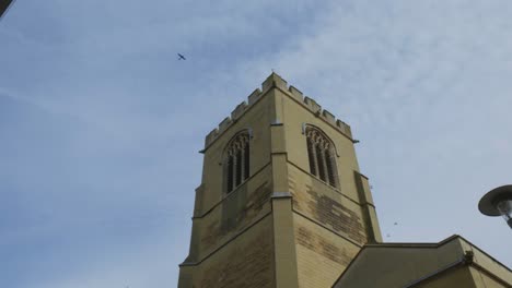 Los-Pájaros-Se-Elevan-A-Través-Del-Cielo-Azul-Sobre-Los-Edificios-Históricos-En-Cambridge,-Inglaterra