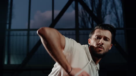 Stylish-dancer-looking-camera-evening-class.-Sportswear-man-dancing-indoors.