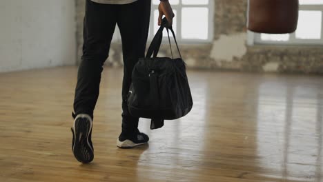 Cropped-view-of-and-athlete-walking-into-room-with-a-bag,-ready-to-start-training