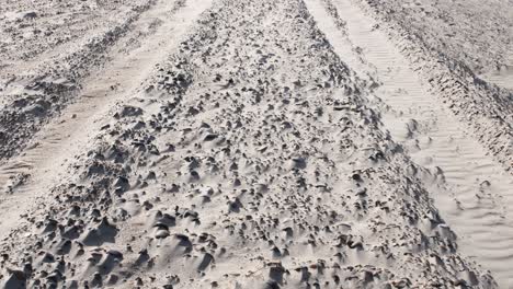 Inclinación-Hacia-Arriba-De-Las-Marcas-De-Neumáticos-De-Un-Vehículo-Del-Desierto-Conduciendo-En-Un-Desierto-Arenoso-Durante-La-Luz-Del-Sol