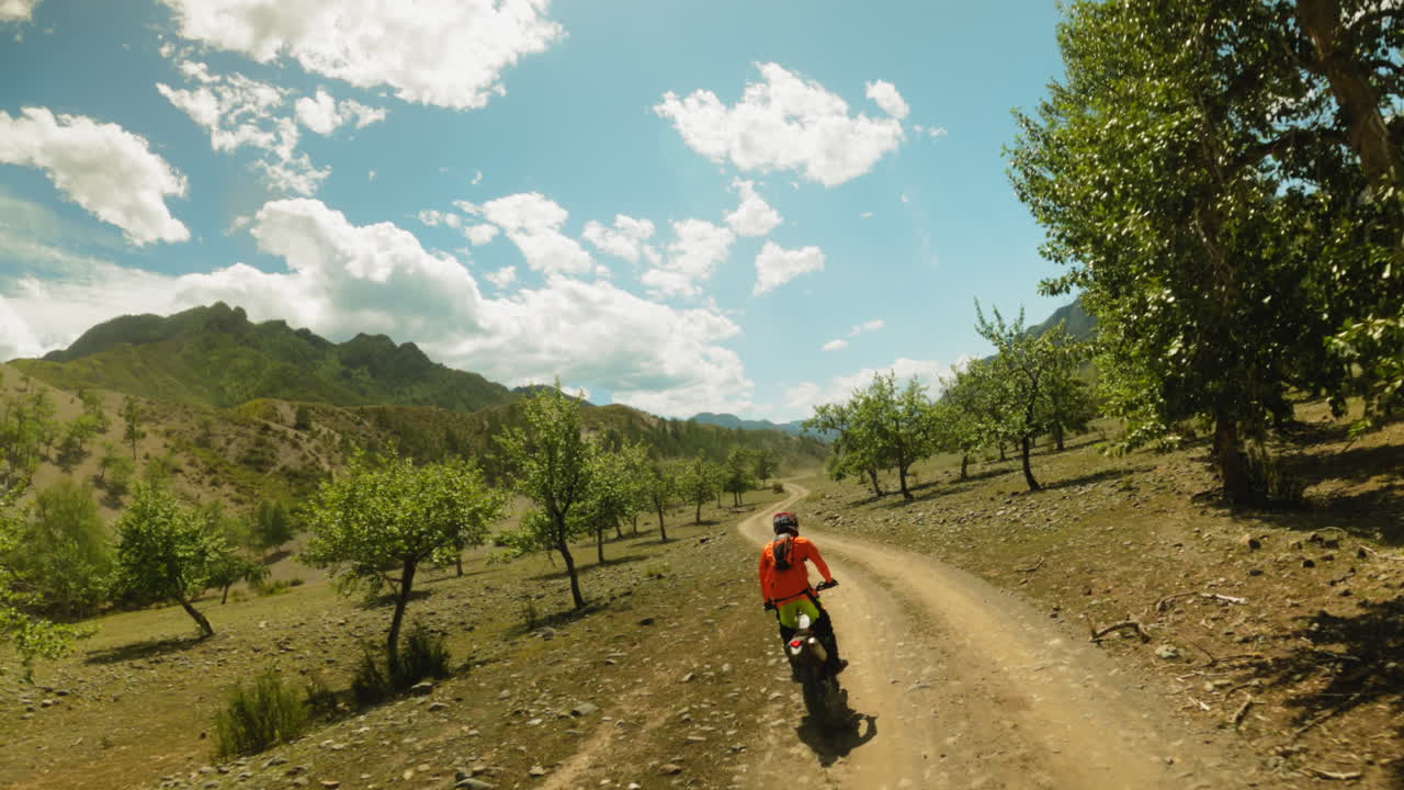 스포츠맨이 농촌 도로를 따라 젊은 나무 fpv를 가로질러 오토바이를 타고, 오토바이에 탑승한 프로 오토바이 운전자는 고지대 시골을 가로지르고, 모토크로스 훈련을 한다.