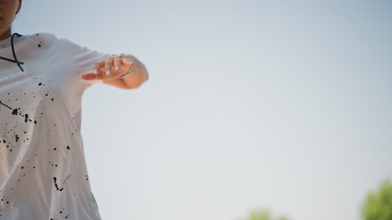 Focused performer adjusting equipment, Close view of dancer setting up gear outdoors, Individual in urban setting getting ready for dance or exercise routine with electronic devices