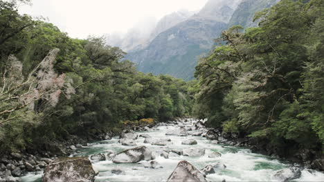 River-waters-cascade-over-rugged-boulders,-tracing-back-to-snow-capped-mountain-peaks-towering-above