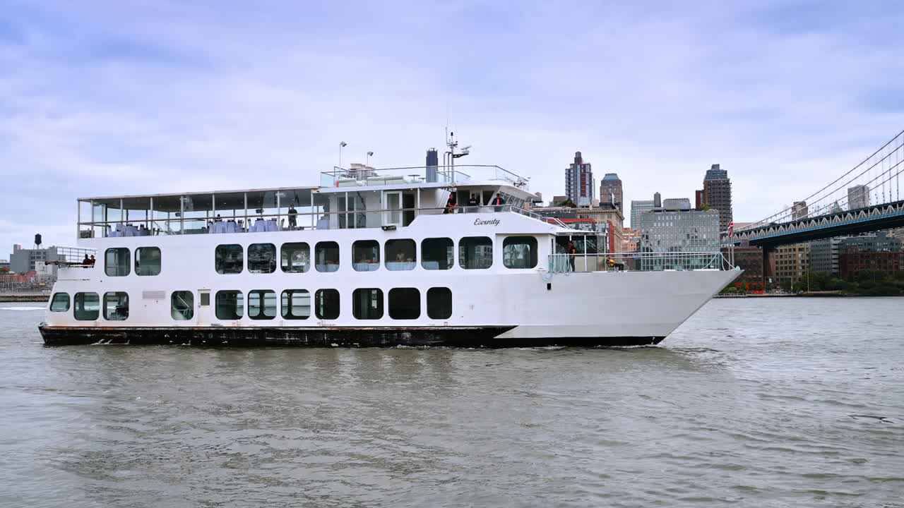 New York, VS, 8 november 2025: Wit cruiseschip op de East River. Passagiersschip vaart langs de waterkant van Manhattan met op de achtergrond de bogen van een brug