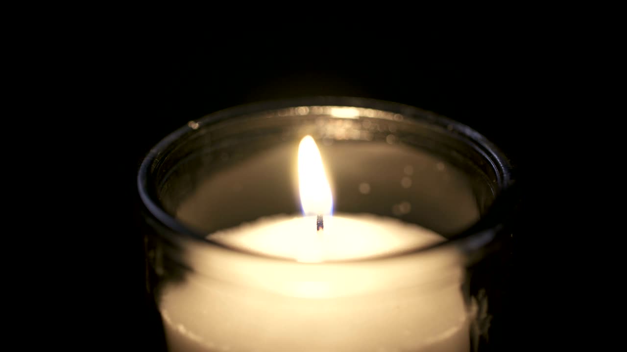 Filmato macro in slow motion di una candela bianca su sfondo scuro