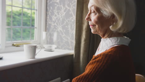 Senior-Couple-Sitting-By-Radiator-At-Home-With-Man-Putting-Reassuring-Hand-On-Woman's-Shoulder