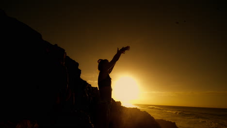woman practicing yoga at sunset by the ocean