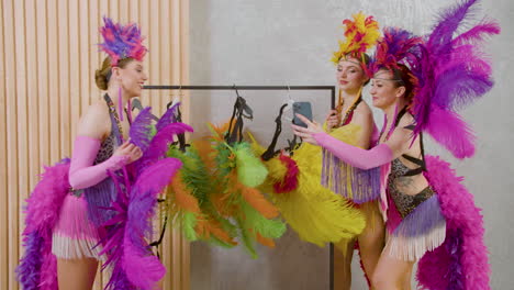 two cabaret dancer choosing the outfits for the show and her colleague takes a selfie photo with them