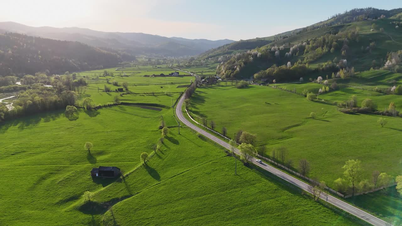 Drone captures rural landscape with green fields near Humorului Monastery at sunset