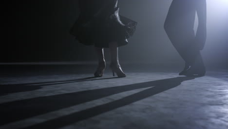 unknown dancers legs moving on floor. dance couple feet dancing on dark stage.