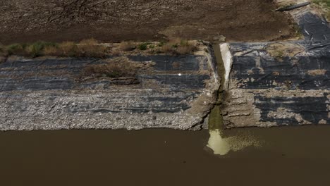 aerial shot of a manure lagoon over flow spout draining into the next cell