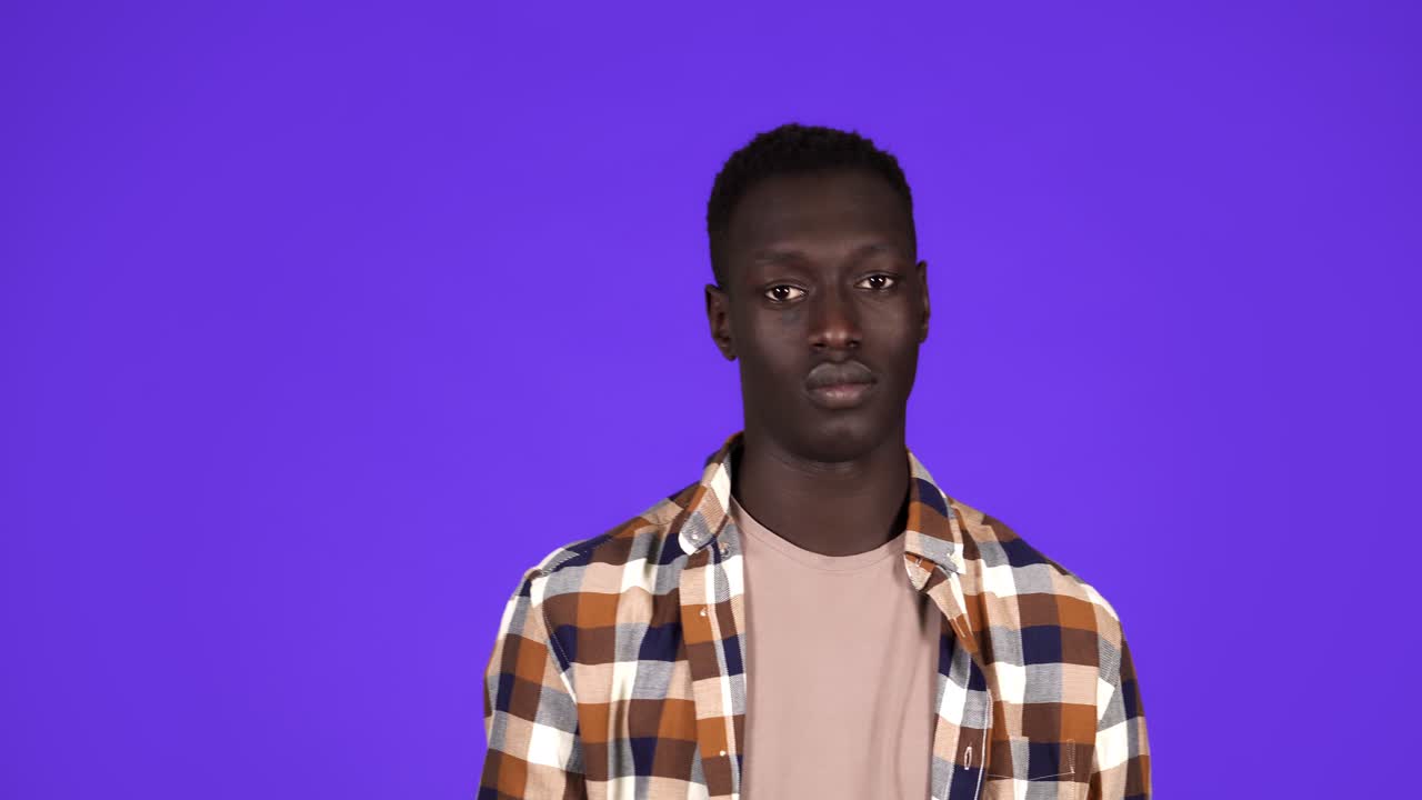 Cheerful Afro-American man showing call me gesture, getting acquainted on party or flirting. Isolated over blue background