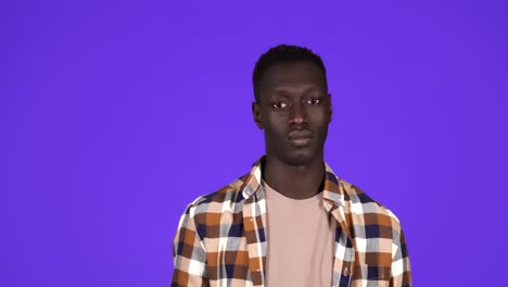 cheerful afro-american man showing call me gesture, getting acquainted on party or flirting. isolated over blue background