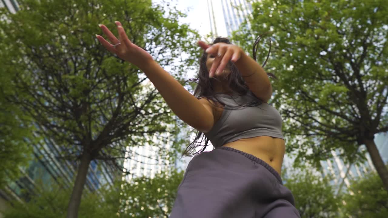 bailarina callejera funky con gran cuerpo físico estilo libre al aire libre sigue sonriendo disfrutando de sus movimientos en el medio de londres con edificios altos a cámara lenta