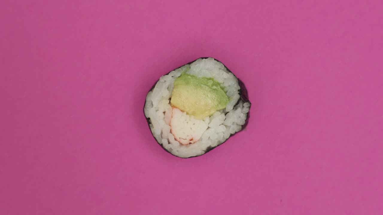 un rollo de sushi girando sobre un fondo rosado