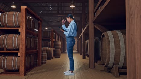 full body side view of an asian female professional worker standing with her tablet in cellar of winery, she is nodding her shead with dissapionted