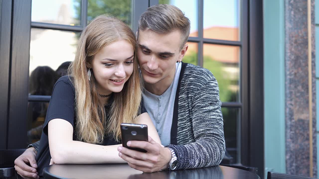 Couple looking at a smartphone in a cafe