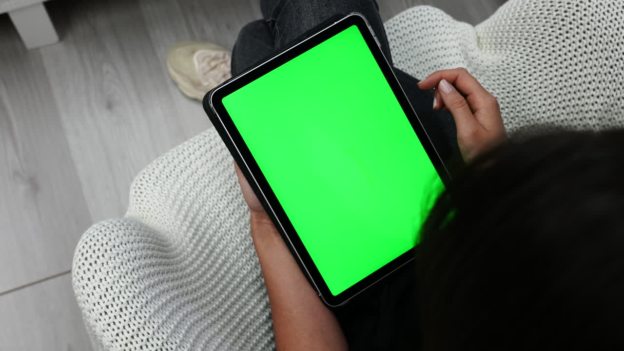 mujer sosteniendo una tableta y deslizando el dedo en la pantalla táctil con pantalla verde, vista superior