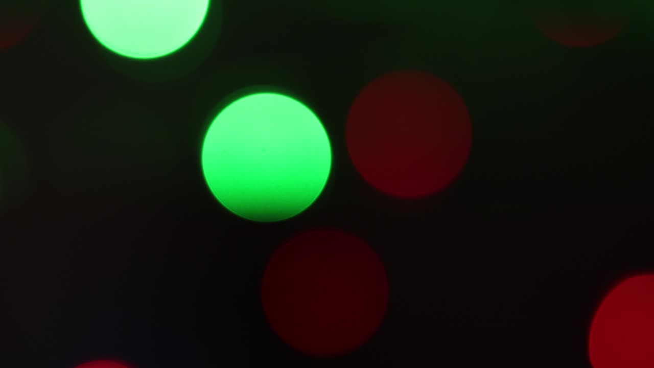 Christmas blur background. Shimmering colored circles defocused christmas lights video. Multicolored light leaks 4k footage on black background