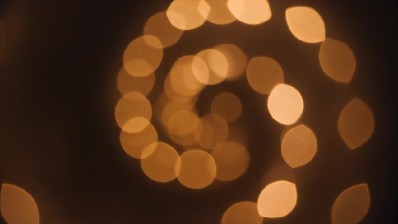 Spirale astratta di luci bokeh dorate su sfondo scuro