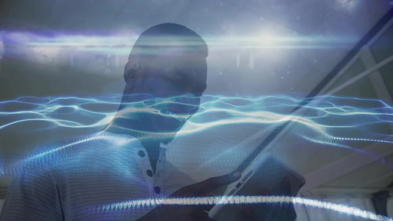 Man in tech workspace tapping and sliding tablet screen guiding blue waveform visualization
