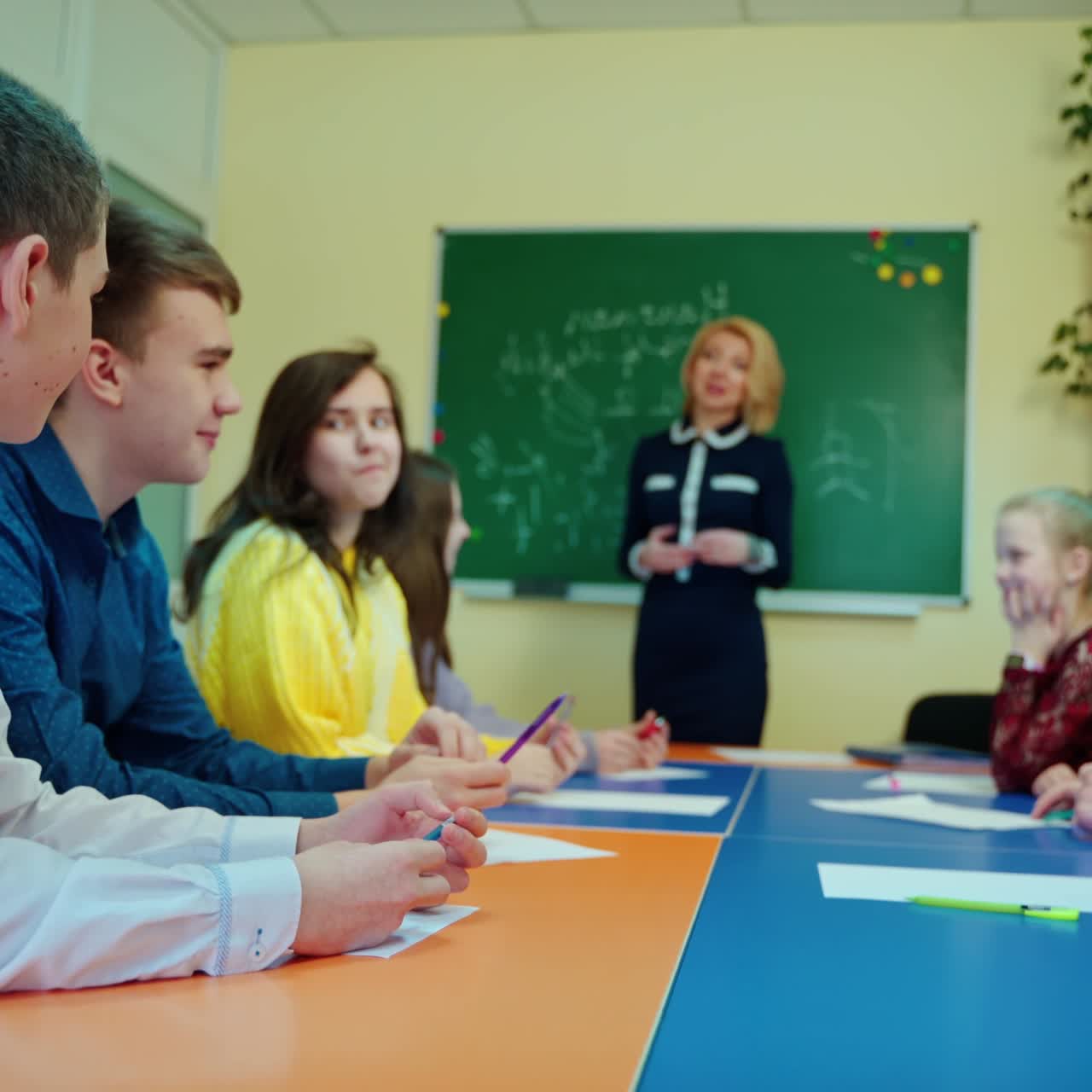 Schoolchildren and a teacher in the classroom. Positive atmosphere during the lesson in the middle school. Education at school.