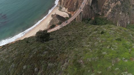 luftdrohnen-stockvideo der autobahn bixby bridge mit wasser und ufer unten in big sur, monterrey, kalifornien