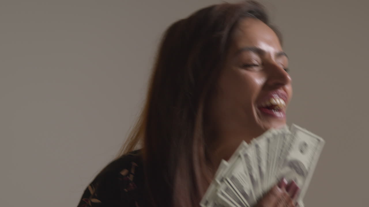100달러 지폐를 한 손에 들고 현금 상을 수상하는 흥분한 여자의 스튜디오