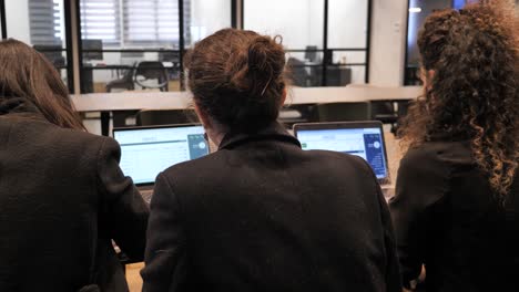 tres empresarias que trabajan en computadoras en oficinas corporativas modernas
