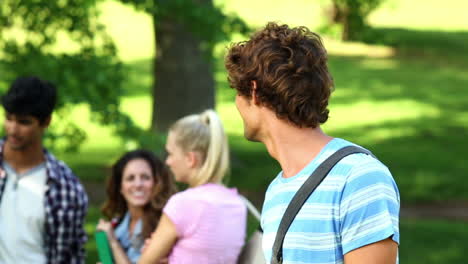 estudiante sonriendo a la cámara con amigos de pie detrás de él