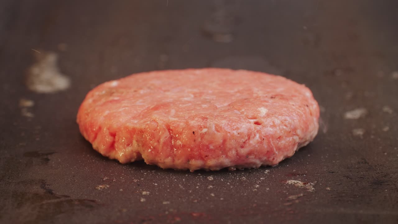 Cooking American fat smash burger on grill close-up. Beef or pork cutlet smashing by burger press. The chef in kitchen of the restaurant making cutlets for burgers - smash burger beefsteak. Fast and street food concept. High quality 4k footage