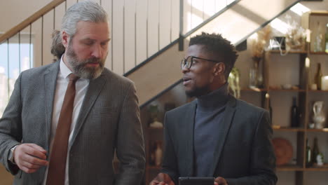 diverse businessmen walking with tablet and having discussion