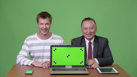 mature japanese businessman and young scandinavian businessman working together