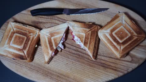 deliciosos sándwiches bellamente colocados en una tabla de madera mientras se pone un cuchillo a un lado