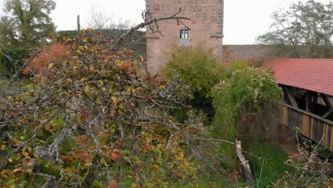 Eine-Drohne-Senkt-Sich-Gegen-Den-Turm-Und-Passiert-Einen-Baum,-Und-Auf-Dem-Video-Ist-Auch-Eine-überdachte-Brücke-Zu-Sehen