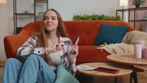 smiling happy young woman counting money cash, calculate domestic bills at home satisfied of income