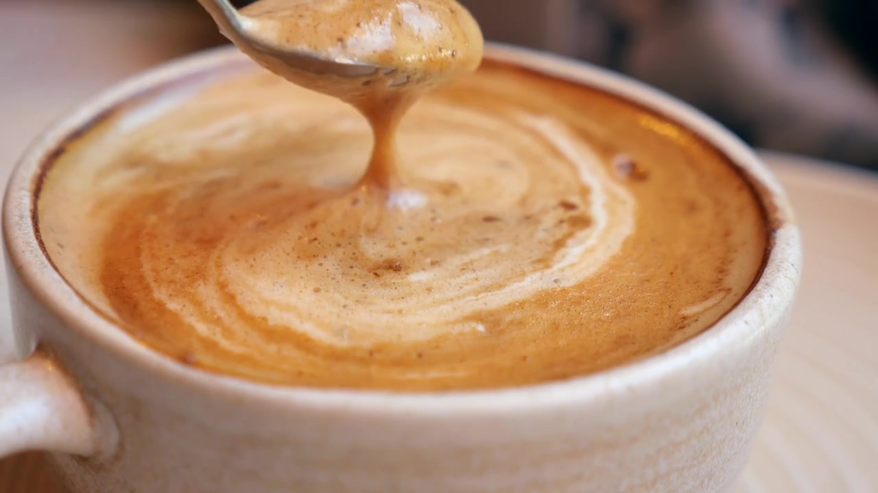 Persona che mescola un latte cremoso in una tazza di ceramica